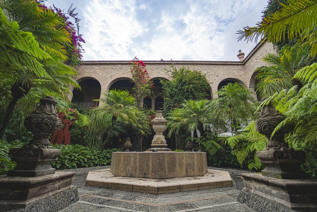 Patio colonial con fuente de piedra, arcos y buganvilias, Hotel de la Soledad